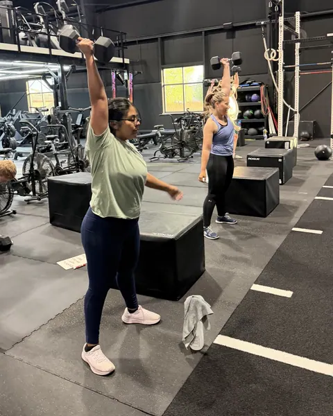 Coach guiding a member on the Iron Forge training floor